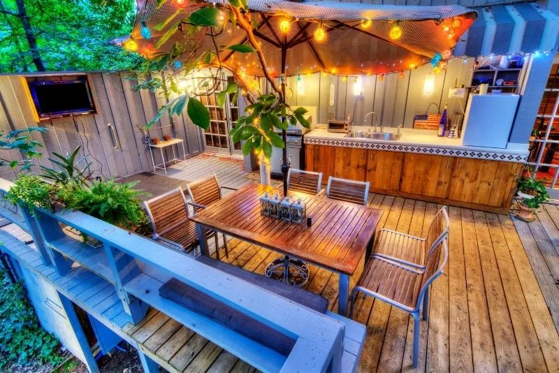 Outdoor kitchen and dining deck lit with festoon lighting under a market umbrella