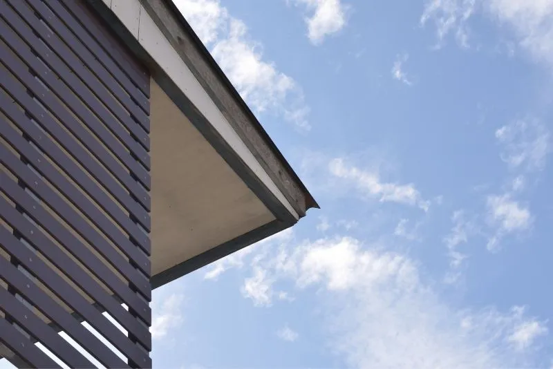Close-up of a slatted timber-clad roofline and eave against a clear sky