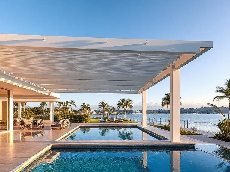 Modern motorised pergola shading a waterfront pool area
