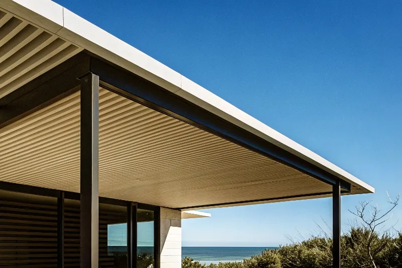 Modern black aluminium pergola with louvred roof attached to contemporary Gold Coast home with ocean view, demonstrating sleek architectural integration