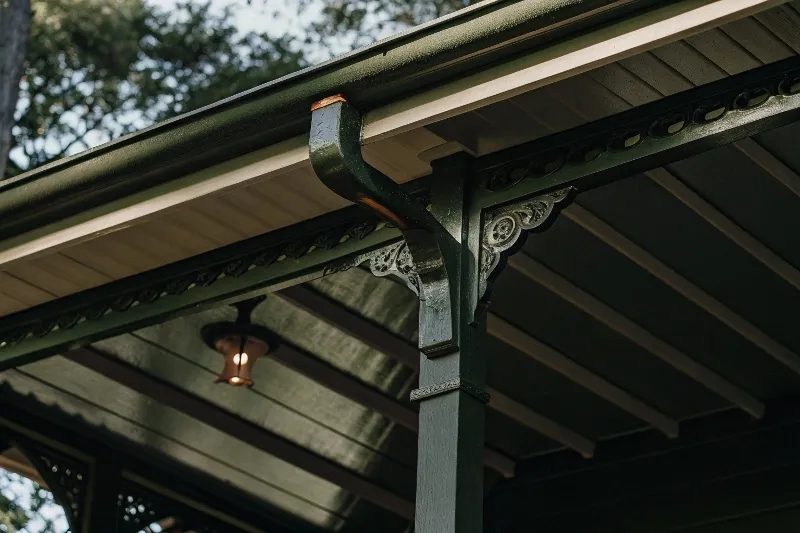 Detailed view of ornate timber joinery and decorative brackets on traditional Queenslander pergola with integrated outdoor lighting