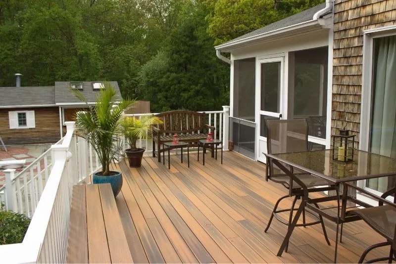 Raised timber deck with dining furniture beside a screened porch