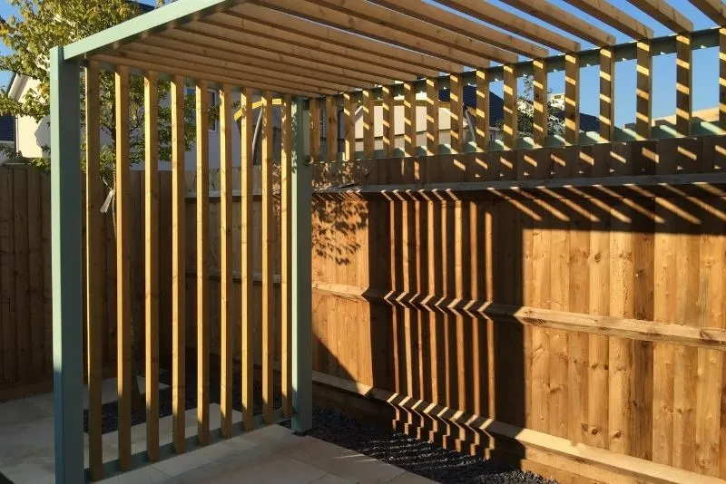 Combination timber and metal-framed pergola over a paved patio area