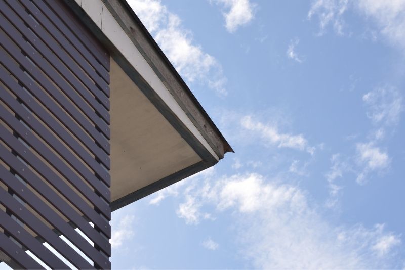 Close-up of a slatted timber-clad roofline and eave against a clear sky
