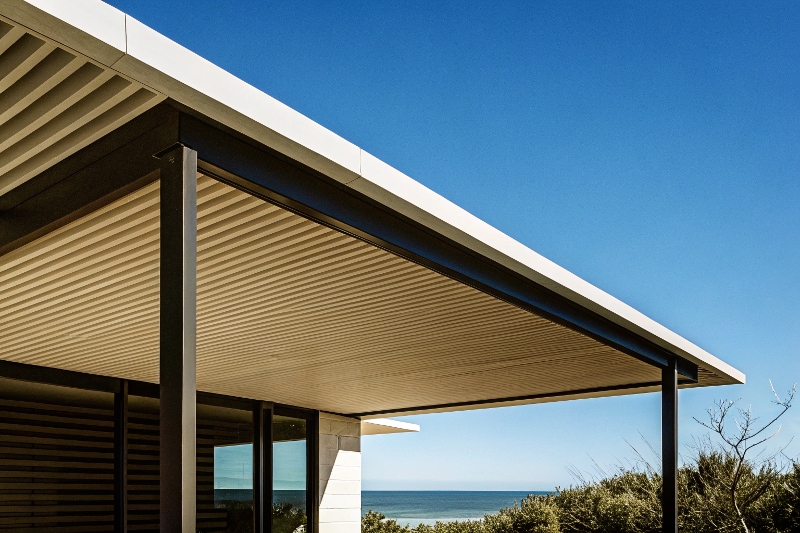 Modern black aluminium pergola with louvred roof attached to contemporary Gold Coast home with ocean view, demonstrating sleek architectural integration